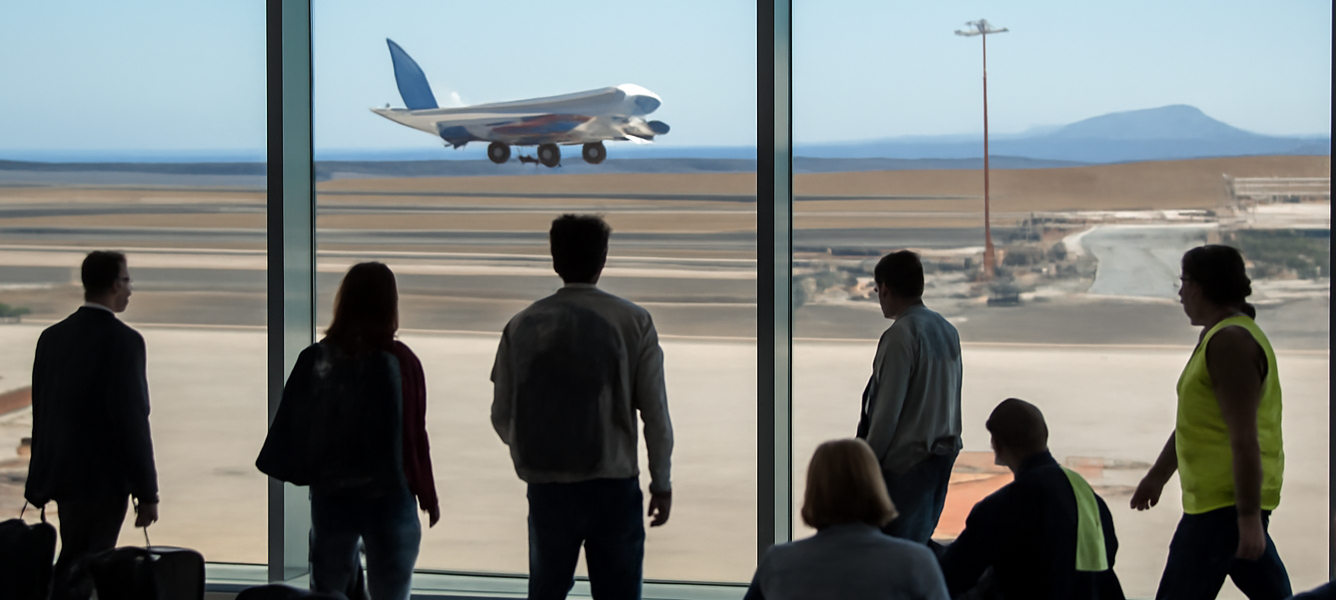 Terminal dell’aeroporto di Fuerteventura con aereo in atterraggio e passeggeri sulla pista